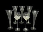CRISTAIS e VIDROS, lote com sete (7) taças, sendo: A) 2 para vinho confeccionadas e cristal translucido com bojo cinzelado por folhagens e frisos em baixo relevo, haste cilíndrica, apoiada sobre base circular, medindo 23x6,5cm e B) 5 tulipas confeccionadas em vidro translucido de 2 modelos, sendo 2 lisas e 2 em gomos torcidos, medindo 25x8cm.