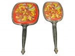 METAL PRATEADO, duas (2) peças, sendo: A) 1 escova e B) 1 espelho confeccionados em metal prateado com cinzelado de perolados, folhagens e caneluras, decoração em vinil com pintura floral em policromia, medindo 29cm e 25,5cm.