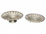 METAL PRATEADO, lote com duas (2) fruteiras confeccionadas em metal espessurado a prata das manufaturas REGIA e AUREA, ambas com cinzelado floral em vazados, ambas bordas em ondulações, uma de pé (apresentando falhas na prateação e mossa na base) e outra apoiada sobre 3 pés curvos, medindo 5x24cm e 10x25cm.