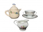 PORCELANAS e FAIANÇA, lote com três (3) peças, sendo: A) 1 bule para chá confeccionado em faiança vitrificada na tonalidade branca moldada por caneluras e pega da tampa no feitio de concha, bicado no bico, medindo 16x18x10cm, B) 1 xícara de consumer com seu respectivo pires confeccioandos em porcelana da manufatura SCHMIDT, decorado por guirlanda floral e realces em azul com filetes em ouro, medindo 7,5x17x12,5cm e C) 1 leiteira da marca REAL, confeccionada em porcelana branca com pintura de flores e folhagens em policromia e filetes em ouro, medindo 9x13x7cm.