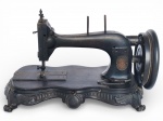 DIVERSOS, uma (1) máquina de costura SINGER, com estrutura em ferro fundido, acabamento escuro, com volante lateral, braço curvo e base ornamentada, apresentando trabalho decorativo em relevo, típica produção do final do século XIX / início do século XX, vendida no estado da foto, medindo 21x39x26cm.