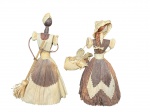ESCULTURAS, duas (2) esculturas representando figuras femininas, confeccionadas artesanalmente em palha trançada, representando personagens do cotidiano rural. Uma das figuras porta vassoura, enquanto a outra carrega cesto, ambas com vestimentas em palha natural e tingida em tons terrosos, com aplicação de detalhes manuais e acabamento rústico, medindo 19cm e 20cm.