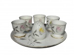 PORCELANA EMANO, sete (7) peças confeccionadas em porcelana na tonalidade branca com pintura de flores e folhagens em policromia e borda filetada em ouro, apresenta falhas na douração, sendo: A) 5 porta ovos, medindo 5x5cm, B) 1 saleiro no feitio de ovo, medindo 6cm e C) 1 bandeja redonda, medindo 20cm.