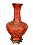 DIVERSOS, um (1) vaso bojudo e sextavado, confeccionado em laca em tonalidade vermelho cinábrio, ricamente entalhado em relevo com cenas orientais tradicionais, representando paisagem com arquitetura, vegetação e figuras, além de painéis com motivos geométricos e simbólicos no gargalo, medindo 26cm de altura.