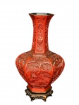 DIVERSOS, um (1) vaso bojudo e sextavado, confeccionado em laca em tonalidade vermelho cinábrio, ricamente entalhado em relevo com cenas orientais tradicionais, representando paisagem com arquitetura, vegetação e figuras, além de painéis com motivos geométricos e simbólicos no gargalo, medindo 26cm de altura.