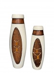 CERÂMICAS, dois (2) vasos confeccionados em cerâmica de tonalidade clara, com aplicação frontal de elementos em madeira e detalhes ornamentais em relevo, formando composição geométrica e étnica. Gargalos com acabamento em faixa amadeirada, conferindo contraste visual ao conjunto, medindo 38x8cm e 30x6cm, 1 falta tacho metálico e outro com corda arrebentada.