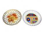 PORCELANAS, dois (2) pratos decorativos confeccionados em porcelana na tonalidade branca com borda em vazados, sendo: A) 1 decorado por cacho de uva e castanhas em policromia e borda filtada a ouro, medindo 19,5cm e B) 1 com decoração abstrata em policromia, medindo 19cm.