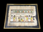 QUADRO, uma (1) reprodução em papiro, representando cena de inspiração egípcia, com figuras humanas e divindades zoomórficas em composição ritualística, acompanhadas de escrita hieroglífica, moldura em metal dourado com proteção em vidro, medindo 42x52,5cm. Desgastes no papiro.