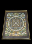 QUADRO, uma (1) reprodução pictórica de inspiração oriental, apresentando composição mandálica ricamente detalhada, com figuras simbólicas dispostas de forma radial e elementos decorativos em cores variadas, moldura em metal dourado com proteção em vidro, medindo 37,5x31cm.