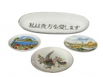 PORCELANAS, lote com quatro (4) peças confeccionadas em porcelana na tonalidade branca, sendo: A) uma (1) travessa oval em porcelana, com inscrição em ideogramas japoneses no interior (tradução livre: Eu amo você), borda com filete em ouro com falhas, medindo 24x9cm, B) dois (2) pequenos pratos decorativos tipo souvenir, decorados com vistas urbanas europeias, identificados como Lugano e Firenze, medindo 10cm e C) uma (1) prato decorativo em porcelana, decorado com cena naturalista de aves e flores, com acabamento esmaltado e filete dourado na borda, medindo 11cm.
