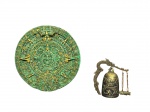 DIVERSOS, duas (2) peças decorativas, sendo: A) um (1) mandala decorativo circular em resina com acabamento em pátina verde e dourada, ricamente trabalhado em alto e baixo relevo, com motivos simbólicos mesoamericanos, inspirado no Calendário Asteca, medindo 18,5cm apresentando figuras, grafismos e elementos radiais e B) um (1) sino decorativo oriental em metal, com corpo ornamentado por dragões em relevo, acompanhado de suporte articulado com figura de dragão, corrente e pequeno badalo, apresentando quebra na haste (possivelmente levava uma base), medindo 10x9cm.