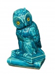 ESCULTURA, uma (1) escultura confeccionada em porcelana na tonalidade azul representando coruja apoiada sobre livros, medindo 18,5cm de altura, leves falhas na esmaltagem.