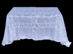 CAMA, MESA & BANHO, uma (1) toalha de mesa em tecido branco, possivelmente em linho, com aplicações de renda floral formando faixas transversais e longitudinais, criando composição em quadros. Apresenta detalhes bordados nas extremidades e acabamento delicado, de caráter clássico e decorativo, indicada para mesa de jantar, aparador ou ambientes tradicionais. Leves sinais de puído e pequeno furo, medindo 300x160cm.