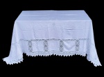 CAMA, MESA & BANHO, uma (1) toalha de mesa confeccionada em tecido na tonalidade branca, com aplicações de renda vazada formando faixa geométrica contínua na parte inferior, além de bordado floral delicado na região superior, medindo 430x150cm.