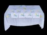 CAMA, MESA & BANHO, conjunto composto por uma (1) toalha de mesa e dez (10) guardanapos, confeccionados em tecido na tonalidade branca, decorados com bordados florais representando flores em tons de amarelo e verde, distribuídos de forma harmoniosa, toalha medindo 206x142cm e guardanapos 41x41cm. Apresenta pequeno furo e leves manchas de guardado.