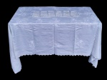 CAMA, MESA & BANHO, conjunto composto por uma (1) toalha de mesa em tecido branco e dez (10) guardanapos, confeccionados em linho, apresentando bordados florais em relevo distribuídos pelo campo da peça. A toalha possui borda recortada em ondas, com acabamento delicado e visual clássico, toalha medindo 240x160cm e guardanapos 37x37cm, levíssimas manchas de guardado.