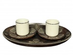 PORCELANAS, lote com três (3) peças, sendo: A) par de xícaras para café confeccionadas em porcelana branca com borda filetada em prata, galeria em metal espessurado com vazados, pires e bandeja moedas em madeira com entalhes de folhagens e aplique de moedas, xícaras medindo 5,5x6,5x5cm e bandeja oval 26x18cm.