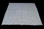 CAMA, MESA e BANHO, uma (1) toalha de mesa retangular confeccionado em linho na tonalidade amarela com bordado floral na tonalidade branca e pontos vazados, apresenta ínfimo furo, manchas de guardado, medindo 200x180cm.