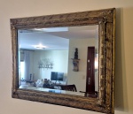 Espelho bisotado emoldurado em madeira nobre entalhado e com douração medindo 70 cm por 95 cm, perfeito estado de conservação.