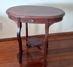 Mesa de apoio oval com ecoração machetada em madeira maciça com uma gavetinha central em perfeito estado de conservação medindo 78 cm de altura por 84 cm por 54 cm.