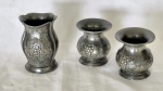 Três vasos em pewter europeu par com decoração com relevos de cachos de uvas e outro floral   medindo em média 9 cm de altura por 8 cm de diâmetro.