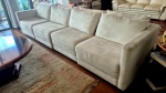 Grande sofá em quatro módulos com duas almofadassoltas no encosto medindo 80 cm de altura no encosto por 345 cm em quatro módulos por 100 ce profundidade, apresenta desgastes em algumas partes no tecido da base visiveis nas fotos.
