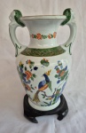 Anfora em porcelana pintada a mão ao gosto  Oriental com duas  alças laterais em forma de Leões e peanha em madeira, decoração com Ave do Paraiso em reserva  ladeado com peonhas e flores de cerejeira medindo 35 cm de altura por 23 cm de diâmetro, em bom estado de conservação duas minimas faltas na barra verde..