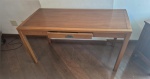 Mesa lisa em madeira e folheado com uma pequena gaveta medindo 74 cm de altura 130 por 57 cm.