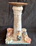 Oficina de Agosto escultura em forma de castiçal base com elementos decorativos em madeira, coluna central torneada com bobeche em ferro e local para fixação de vela, medindo 32 cm de altura por 20 cm por 20 cm.