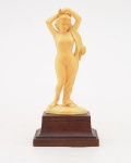 Escultura em marfim europeu, sobre base de madeira, representando figura de nú feminino. Medida: cm.
