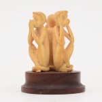 Escultura representando os "três macacos sábios" (Mizaru, Kikazaru e Iwazaru) em marfim sobre base de madeira. Diâmetro da base: cm. Altura total: cm.