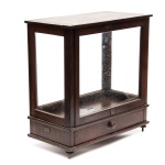 Antiga caixa de balança de precisão para farmácia e/ou ourives, caixa em madeira nobre de época, com os vidros, apresenta porta dianteira e gaveta frontal, Selo da casa Moreno Borlido e Cia. Medidas: 44 x 23 cm. Altura: 47 cm..