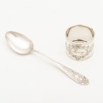 Conjunto de colher de chá e anel porta guardanapo em prata alemã, contraste teor 800 mls. Apresentam inscrição "Lucy". Peso: 22 gramas.