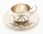 Xícara e pires em prata portuguesa estilo art nouveau, contraste "Javali II" teor 833 mls. Marca da ourivesaria Aliança. Apresenta inscrição "Adélia" na xícara. Diâmetro do pires: 12 cm. Alura da xícara: 5 cm. Peso: 104 gramas.