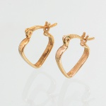 Par de brincos confeccionado em metal espessurado a ouro, formado por aros vazados de contorno cordiforme, estruturados em fio contínuo de seção circular. Sistema de fecho articulado tipo alavanca, com pino basculante e charneira lateral, integrado à armação superior. Conjunto simétrico, com elementos móveis independentes, próprio para uso auricular. Fabricação compatível com joalheria de produção seriada. Estado de conservação compatível com uso. Medida: 1,5 x 1,2 cm.