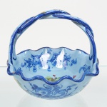 Cesto executado em faiança portuguesa, bojo hemisférico de borda recortada em contorno ondulado e asa superior fixa em arco entrelaçado, moldada integralmente à peça, superfície interna e externa com decoração floral policromada, aplicada por pintura manual, composta por ramagens, flores estilizadas e volutas, delimitadas por filete azul-cobalto no lábio e na asa. Marca manuscrita sob a base, com inscrição Pedrus Alcobaça 501, aplicada sob o vidrado. Produção em faiança portuguesa, atribuída à Fábrica de Faianças de Alcobaça, Portugal, meados do século XX. Apresenta um ínfimo desgaste na borda, vide foto. Medidas: Alt.: 13 x Diam.: 15 cm.