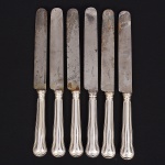 Christofle, Paris - França(Fundada em 1830 por Charles Christofle). Luxuoso conjunto de facas grandes confeccionadas em metal espessurado à prata, fabricação francesa do início do século XX, executado ao estilo do período Louis Philippe. Padrão "Chinon", usado a partir de 1862, conhecido anteriormente como "filet" ou "vieux Paris". Cabo apresenta "ombros" e margem contornada por frisos de terminação cordiforme sobre extremo arredondado. Lâminas em aço marcada CHRISTOFLE A PARIS(apresentam sinais de oxidação). Composto de seis(06) unidades. Marca da manufatura puncionada no verso do cabo. Med.: Comp. 26 cm.