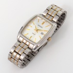 Relógio de pulso com caixa tonneau em aço inoxidável, vidro plano, coroa lateral para ajuste. Mostrador retangular de coloração clara, com marcadores lineares aplicados, ponteiros centrais para horas, minutos e segundos, e janela de data posicionada às três horas. Inscrições SEIKO, 100M e MOVT JAPAN. Movimento a quartzo calibre 7N82, fabricação japonesa. Resistência à água indicada para 10 bar / 100 metros. Pulseira metálica articulada, em aço inoxidável, com elos centrais em tom dourado, fecho dobrável com trava, assinado SEIKO. Tampa posterior contendo gravações: SEIKO, WATER RESISTANT 10 BAR, STAINLESS STEEL, 7N82-0G00, MOVEMENT JAPAN, numeração de série. Não está funcionando. Medida da caixa: 4 x 3 cm.