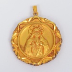 Medalhão pendente de formato circular, confeccionado em metal espessurado à ouro, com borda recortada em perfil lobado e aro interno circular em relevo. Argola de suspensão articulada, integrada a contrapino tubular estriado. Anverso com representação em baixo-relevo do Sagrado Coração de Jesus, com halo circular, indumentária frontal e emblema do Coração Sagrado, composto por coração anatômico estilizado, coroa de espinhos, chama superior e cruz axial. Reverso com representação em baixo-relevo de Nossa Senhora com o Menino Jesus, ambos coroados, com nimbos radiantes, a figura mariana portando o Menino ao braço esquerdo. Execução por moldagem em matriz, com relevo contínuo em ambas as faces. Peça devocional destinada a corrente ou colar. Medida: Diam.: 4,5 cm.