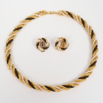 Colar estruturado em feitio de corda torcida, formada por fios em metla banhado à ouro helicoidais, entrelaçados com contas pretas e brancas, distribuídas de maneira alternada ao longo do comprimento, fecho rosqueável cilíndrico, com encaixe por rosca, integrado às extremidades do colar. Brincos em formato circular com composição correspondente ao colar, fecho tipo presilha. Medidas: Colar: Comp.: 19,5 cm. Brincos: Diam.: 2 cm.