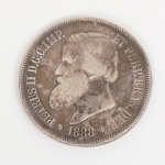 NUMISMÁTICA. Moeda do Período Imperial Brasileiro, valor de face 2000 Réis, IV FAMÍLIA, 5 TIPO 1886 - 1889, bordo serrilhado, executada em prata 917 milésimos. Anverso (Frente): Busto de D. Pedro II, voltado à esquerda. Inscrição em latim: PETRUS II D. G. C. IMP. ET PERP. BRAS. DEF. (Pedro II, pela Graça de Deus, Imperador e Perpétuo Defensor do Brasil). Ano de cunhagem: 1889, entre uma esfera armilar e uma cruz da Ordem de Cristo. Reverso: As Armas do Império (escudo com a esfera armilar, estrelas e a Cruz da Ordem de Cristo). Inscrição acima: DECRETO DE 1870. Valor facial: 2000 RÉIS. Símbolos: ramos de café e tabaco, unidos por um laço, e uma balança e um caduceu (símbolos do comércio). Medida: Diam.: 37 mm. Peso: 25,3 gramas.