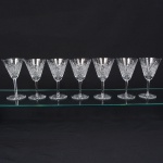 Exuberante conjunto de taças de pé alto, para vinho branco, em cristal europeu, provavelmente   tcheco, diáfano e incolor. Bojo obcônico, profusamente talhado com padrão de folhas estilizadas, estrelas e formas geométricas em relevo, organizado em painéis verticais facetados, fuste longo de seção hexagonal, base circular, fundo com lapidação radial em estrela, com raios  partindo do centro em disposição simétrica. Composto de sete(07) unidades. Medidas: Alt.: 18 x Diam.: 10 cm.