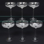 Belíssimo conjunto de taças de pé alto, para champanhe, executado em fino cristal europeu, diáfano e incolor; bojo hemisférico, fundo preenchido e talhado com flor acentinada, fuste tubular alongada sobre base circular. Composto de seis(06) unidades. Medida: Alt.: 19 x Diam.: 11,5 cm.