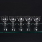 Conjunto de taças de pé baixo, para vinho tinto, em cristal, diáfano e incolor; bojo hemisférico, fuste em anel elipsóide, base circular. Composto de cinco(05) unidades. Medidas: Alt.: 10 x Diam.: 9 cm. Apresentam bicados na borda.