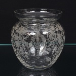 Vaso executado em cristal, diáfano e incolor, gravado com composição de motivo floral, bojo globular seguido de borda elevada. Medidas: Alt.: 9,5 x Diam.: 8,5 cm. Apresenta minúsculo bicado na borda.