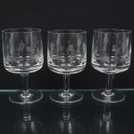 Três(03) taças de pé alto, para vinho tinto, em vidro, translúcido e incolor; bojo de formato cilíndrico, ricamente talhado com motivo de flores estilizadas, fuste tubular sobre base circular. Medidas: Alt.: 13,5 x Diam.: 7 cm.