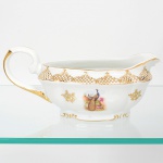 Porcelana Real, Mauá - SP(Fundada em 1943 por Fritz Erwin Schmidt). Belíssima molheira navicular em porcelana nacional da década de 1950/60, esmaltagem vítrea na cor branca, decoração composta por cena com casal de pavões, pousados entre ramos, flores e folhagens, executada em estampagem policromada; ornada por motivos fitomórficos e treliçados em douradura, distrubuídos em reservas,  e filete contínuo acompanhando o contorno da borda, vertedouro ondulado e revirado para fora, alça lateral em voluta coberta por folhagem. Marca da manufatura no verso. Meds.: Molheira: Alt. 10 x Comp. 21,5 x Larg. 11,5 cm.