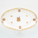 Porcelana Real, Mauá - SP(Fundada em 1943 por Fritz Erwin Schmidt). Belíssima travessa oval em porcelana nacional da década de 1950/60. Esmaltagem vítrea na cor branca, decoração composta por cena central com casal de pavões, pousados entre ramos, flores e folhagens, executada em estampagem policromada; orla ornada por motivos fitomórficos e treliçados em douradura, distrubuídos em reservas, com friso circular interno e filete contínuo acompanhando o contorno da borda. Medidas: Alt.: 4 x Comp.: 37 x Larg.: 22,5 cm.