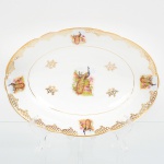Porcelana Real, Mauá - SP(Fundada em 1943 por Fritz Erwin Schmidt). Belíssima travessa funda de fotrmato oval em porcelana nacional da década de 1950/60. Esmaltagem vítrea na cor branca, decoração composta por cena central com casal de pavões, pousados entre ramos, flores e folhagens, executada em estampagem policromada; orla ornada por motivos fitomórficos e treliçados em douradura, distrubuídos em reservas, com friso circular interno e filete contínuo acompanhando o contorno da borda. Medidas: Alt.: 6 x Comp.: 29 x Larg.: 20,5 cm.