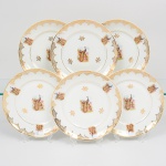 Porcelana Real, Mauá - SP(Fundada em 1943 por Fritz Erwin Schmidt). Belíssimo conjunto de pratos rasos em porcelana nacional da década de 1950/60. Esmaltagem vítrea na cor branca, decoração composta por cena central com casal de pavões, pousados entre ramos, flores e folhagens, executada em estampagem policromada; orla ornada por motivos fitomórficos e treliçados em douradura, distrubuídos em reservas, com friso circular interno e filete contínuo acompanhando o contorno da borda. Composto de seis(06) unidades. Medida: Diam.: 24,5 cm.
